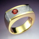 18k yellow gold ring inlaid with Gibeon meteorite and set with 1.01 ct. round brilliant cut, orange/red sapphire. Photo courtesy John Biagiotti, Metamorphosis Design.