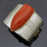 A large cabochon of Pacific salmon colored coral set in sterling silver bracelet with 18k yellow gold accents. Photo courtesy of the artist, Darryl Dean Begay. 